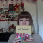 A photograph of a Doll Hospital reader holding up a print copy of Doll Hospital Issue One